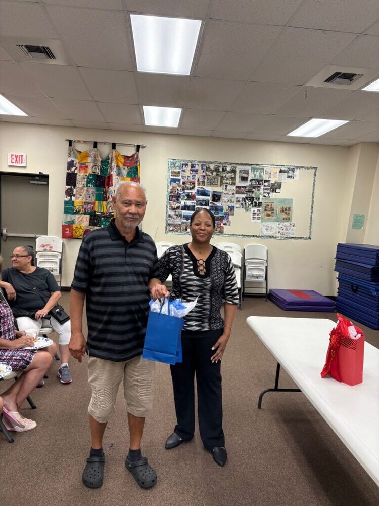 A man and woman smile for a photo holding a gift bag.